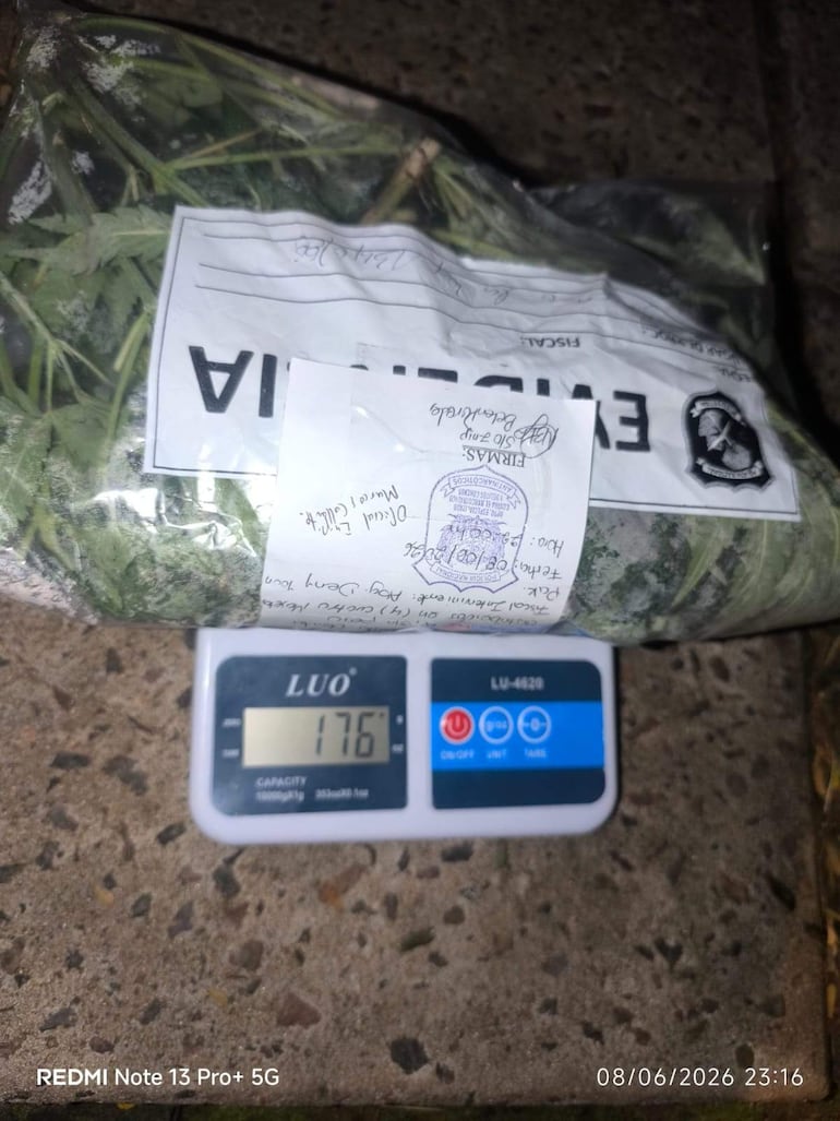 Paquete sellado de marihuana sobre balanza digital que muestra 176 gramos, en un entorno pavimentado.