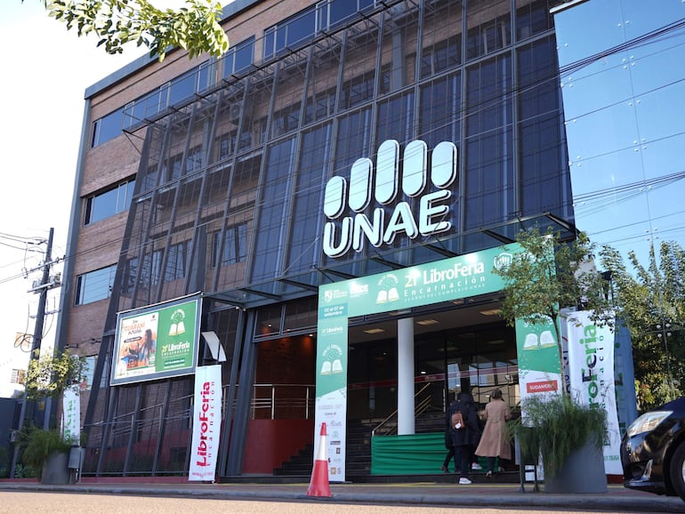 Entrada del Campus de la UNAE decorada con carteles de la Libroferia, sin personas visibles, en un ambiente soleado.