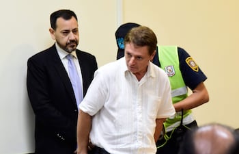 De pie, el aduanero Virgilio Ferreira, uno de los acusados de integrar el esquema de contrabando desbaratado con la Operación Tartufo, es esposado tras conocer su condena a 10 años de cárcel (2023).