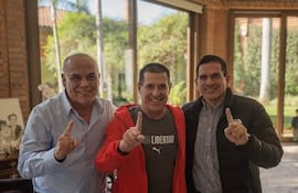 Juan Carlos Baruja con camiseta de Libertad, Horacio Cartes en chaqueta roja y Basilio Núñez en camisa a cuadros, todos sonriendo y levantando un dedo.