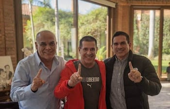 Juan Carlos Baruja con camiseta de Libertad, Horacio Cartes en chaqueta roja y Basilio Núñez en camisa a cuadros, todos sonriendo y levantando un dedo.
