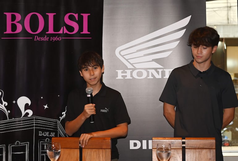 El piloto Oliver Cuevas, de 14 años, se dirige a los asistentes ante la atenta mirada de Nico Torrez.