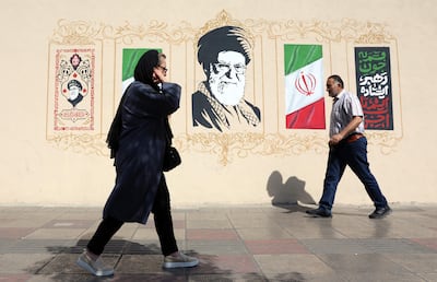 Dos personas caminan frente a un mural de homenaje al fallecido ayatolá Alí Jameneí en Teherán, Irán.