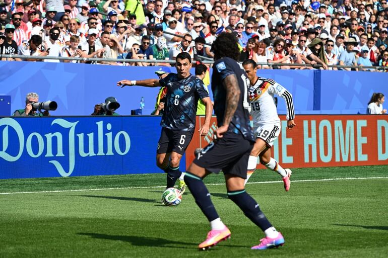 El lateral Junior Alonso retrocede el esférico hacia el zaguero José Canale, ante el asedio del delantero alemán Leroy Sané.