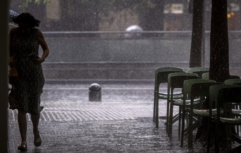 Una mujer corre para refugiarse durante un chaparrón este martes en San Sebastián, País Vasco.