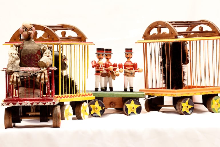 Juguetes de madera en forma de circo con personajes payasos y soldados de juguete en un fondo blanco.