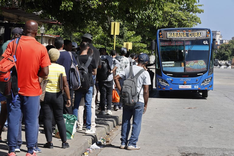 Personas hacen fila para subir a un bus de transporte público, en La Habana (Cuba).