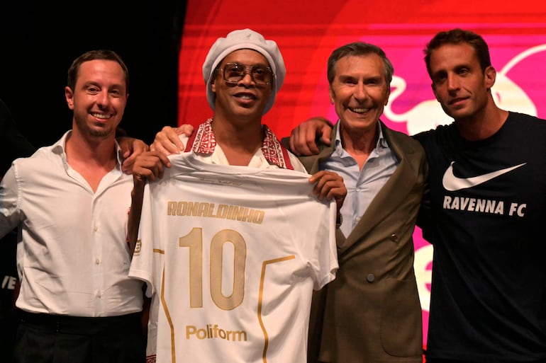 El recién fichado futbolista brasileño Ronaldinho posa feliz con la camiseta del Ravenna FC junto al presidente del club, Ignazio Cipriani (derecha), durante la presentación del equipo en Marina di Ravenna. (Stefano RELLANDINI / AFP)