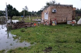 Construcción de ladrillos con ventana cerrada y aire acondicionado, rodeada de césped y charcos de agua en un día nublado.