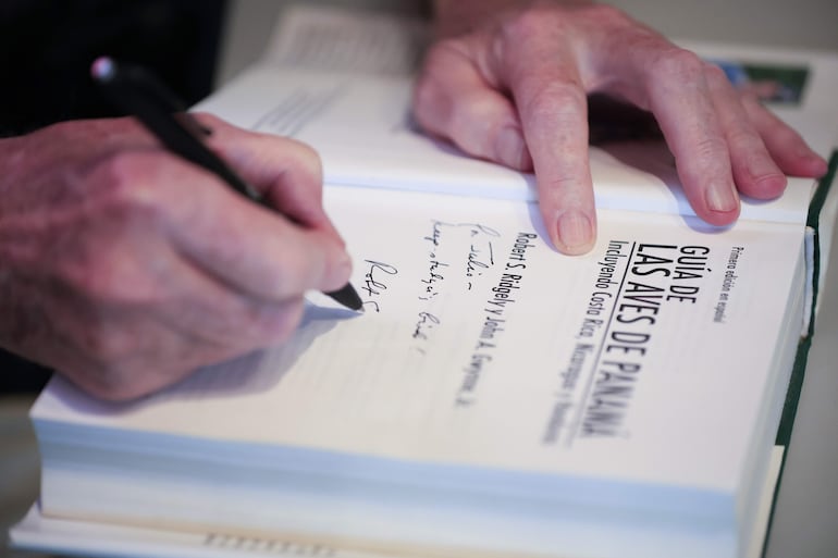 El estadounidense Robert S. Ridgely firma un libro durante una visita al Biomuseo este viernes, en ciudad de Panamá (Panamá).