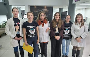 Seis mujeres, entre ellas la Dra. Rossana González, con camisetas que dicen 'Esenciales para el pueblo', en ambiente institucional.
