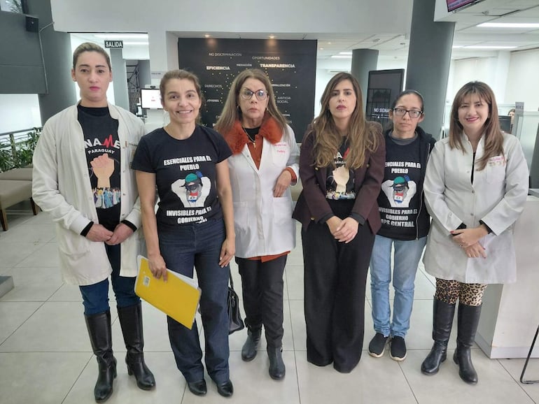 Seis mujeres, entre ellas la Dra. Rossana González, con camisetas que dicen 'Esenciales para el pueblo', en ambiente institucional.
