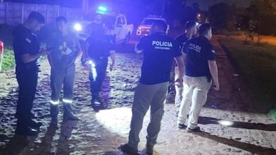 Seis policías, todos con indumentaria de 'POLICÍA', interrogan a un hombre en una zona oscura iluminada por luces de patrulleros.