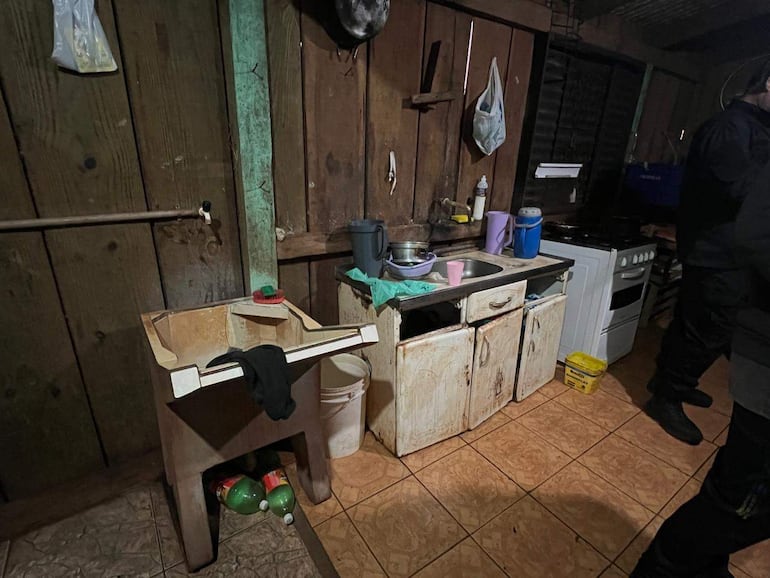 Cocina rústica con mesa de madera, estufa blanca y utensilios de cocina en un ambiente tranquilo.