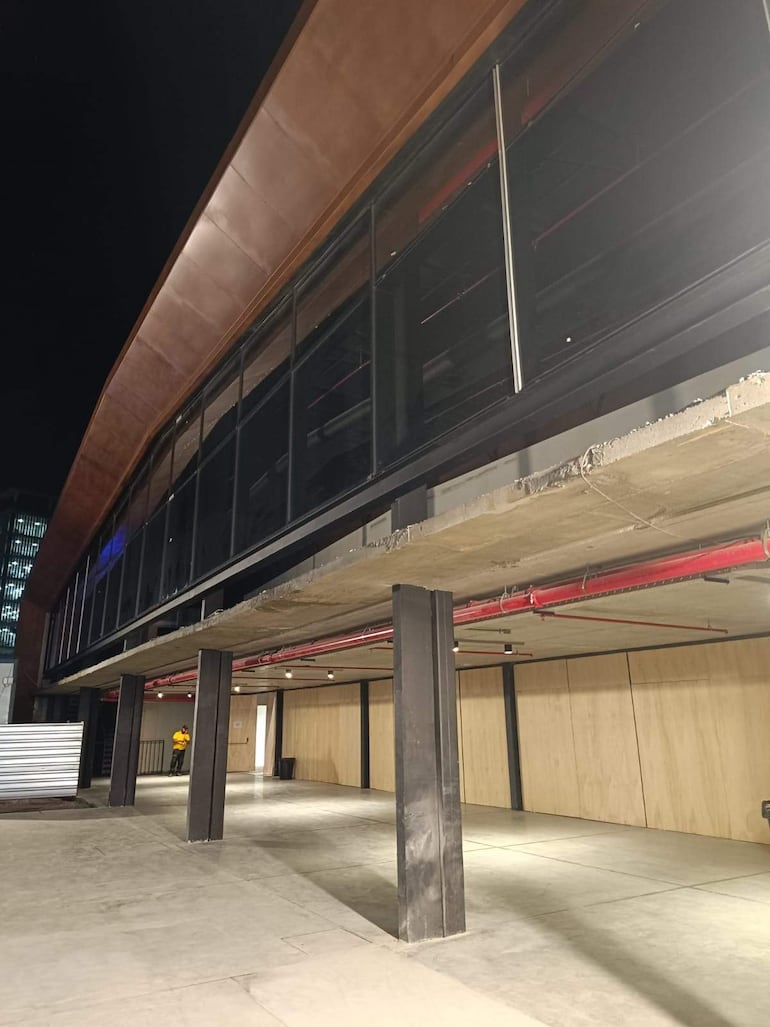 Vista nocturna del Gran Galpón en el Puerto de Asunción, con arquitectura moderna y grandes ventanales iluminados.
