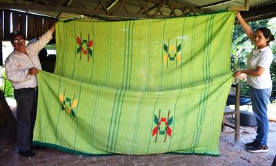 El artesano Genaro Figueredo y la tejedora Dania Sosa exhiben una colcha de hilo bordada.