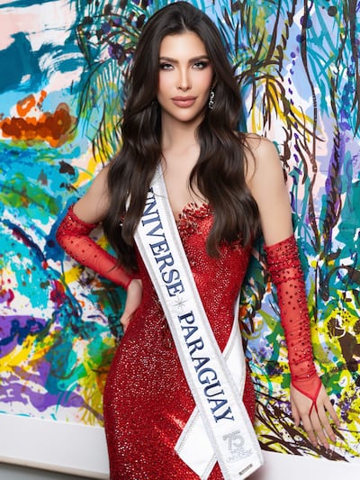 Gretha Matiauda posa en un vestido rojo brillante con banda de Miss Universe Paraguay, en fondo abstracto colorido.
