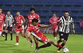 El zaguero Éver Alejandro Fernández barre a los pies del extremo Marcelo Fernández buscando hacerse con el esférico. El capitán rojo, Fernando “Chapa” Martínez, sigue de cerca la acción.