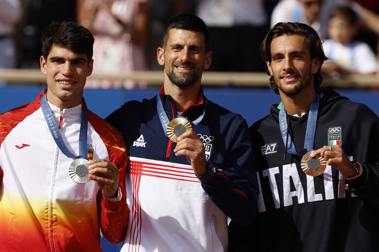 Los tenistas, el serbio Novak Djokovic (c-oro), el español Carlos Alcaraz (i-plata) y el italiano Lorenzo Musetti (d-bronce), posan en el podio tras la final individual masculina de tenis de los Juegos Olímpicos de París 2024.