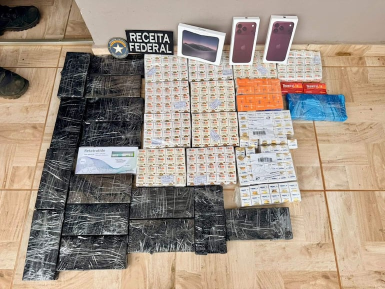 Cartel de 'Receita Federal' y diversas cajas de medicamentos y paquetes sobre el suelo, sin personas presentes.