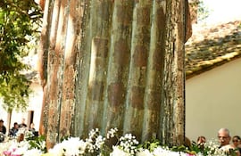 Escultura de la Virgen Santa María de Fe con corona dorada y adornos florales, rodeada de un grupo de asistentes en exterior.