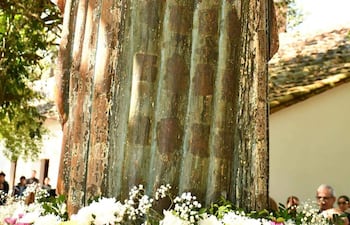 Escultura de la Virgen Santa María de Fe con corona dorada y adornos florales, rodeada de un grupo de asistentes en exterior.