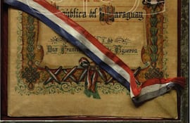 Documento enmarcado titulado 'Himno Nacional de la República del Paraguay' con diseño decorativo y cinta tricolor.