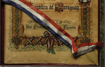 Documento enmarcado titulado 'Himno Nacional de la República del Paraguay' con diseño decorativo y cinta tricolor.
