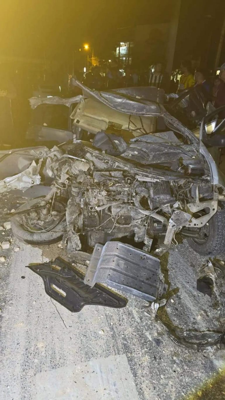 Vehículo descompuesto por accidente en la carretera, rodeado de escombros y con luces artificiales iluminando la escena.