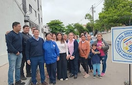 Grupo de quince personas, en su mayoría adultos, reunidos frente a la escuela, algunos llevan abrigos y expresiones decididas.