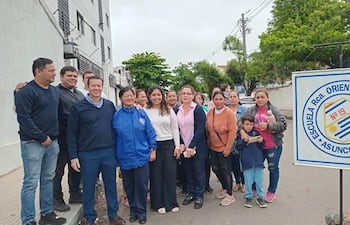 Grupo de quince personas, en su mayoría adultos, reunidos frente a la escuela, algunos llevan abrigos y expresiones decididas.