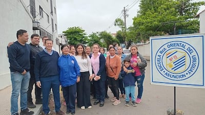 Grupo de quince personas, en su mayoría adultos, reunidos frente a la escuela, algunos llevan abrigos y expresiones decididas.
