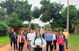 Mujer con blusa blanca y falda negra rodeada de un grupo en la calle, mostrando expresiones de alegría y tranquilidad.
