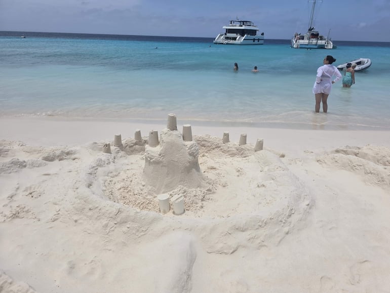 Faro gris con detalles rojos rodeado de un paisaje árido y cielo nublado, sin personas visibles.