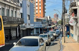Calle urbana concurrida, dos transeúntes casuales, edificios varios y letrero de la pizzería Zampanò visible.