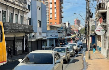 Calle urbana concurrida, dos transeúntes casuales, edificios varios y letrero de la pizzería Zampanò visible.