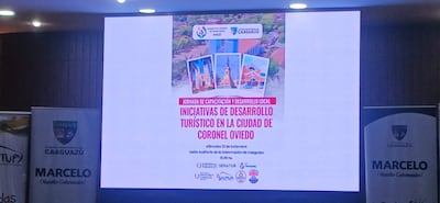 Proyector en auditorio con cartel de jornada de capacitación sobre desarrollo turístico en Coronel Oviedo.