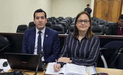 Benítez, con traje oscuro, y Sánchez, con camisa de rayas, sentados frente a un micrófono en un tribunal, tomando notas.