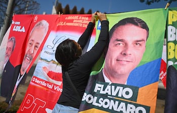 Un mujer organiza en una tienda informal, banderas con la imagen del presidente de Brasil y candidato a la reelección, Luiz Inácio Lula da Silva y del candidato presidencial, Flávio Bolsonaro, este lunes en Brasilia (Brasil). Mientras las encuestas hablan de una extrema igualdad entre el presidente progresista Luiz Inácio Lula da Silva y el ultraderechista Flávio Bolsonaro, analistas consideran que el resultado de las elecciones brasileñas del 4 de octubre depende de un amplio sector que observa el proceso con distancia y escepticismo: los indecisos. EFE/Andre Borges