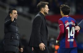 El delantero portugués de Barcelona #14 Joao Felix pasa junto al entrenador argentino del Atlético de Madrid, Diego Simeone, mientras el entrenador español del Barcelona, Xavi (i), espera estrecharle la mano después de ser sustituido durante el partido de fútbol de la liga española entre el FC Barcelona y el Club Atlético de Madrid en el Estadi Olimpic. Lluis Companys en Barcelona el 3 de diciembre de 2023.