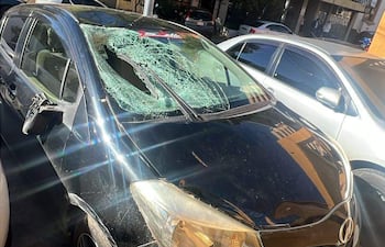Vehículo negro dañado con parabrisas roto estacionado en una calle de Asunción, sin personas visibles en el entorno.