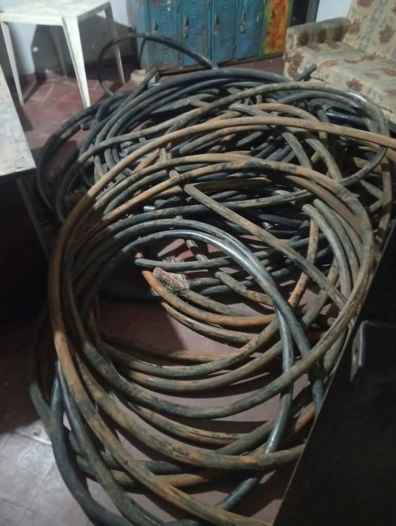 Mangueras enrolladas de diferentes colores en un entorno de trabajo con piso de cerámica y muebles antiguos.