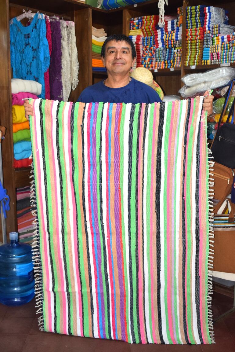 El cliente Oscar Páez muestra con orgullo la colcha de trapo adquirida a la artesana Catalina Marín.