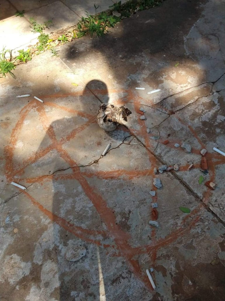 Símbolo pentagramático en el suelo de cemento rodeado de piedras, iluminado por la luz del sol.