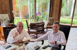 Basilio Nüñez y Horacio Cartes sentados en una mesa, sonrientes y relajados, en un entorno interior elegante.