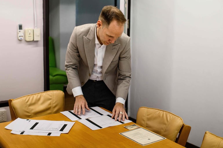 Esta fotografía, tomada el 2 de junio de 2026, muestra al profesor alemán Felix Puelm observando copias impresas de carnés de afiliación al Partido Nacionalsocialista Obrero Alemán (NSDAP) de varios miembros de su familia (abuela, bisabuelo, bisabuela, varias tías abuelas y tíos abuelos), hallados en una base de datos en línea publicada por el semanario alemán Die Zeit.