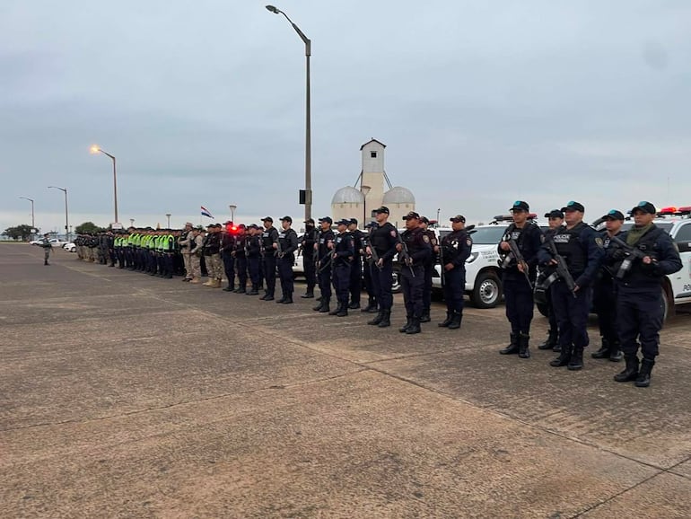 Agentes de seguridad alineados en formación, todos con uniformes oscuros, mientras algunos llevan chalecos reflectantes y armas.