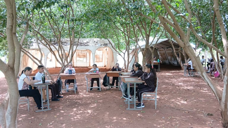Los docentes y alumnos prefieren dar clases bajo árboles que dentro de las aulas carpa, debido a las altas temperaturas.