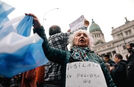Una mujer sostiene una bandera de Argentina durante una movilización este lunes 29 de abril de 2024, en Buenos Aires (Argentina). En el Congreso argentino se realiza el debate del proyecto de la Ley Bases y Puntos de Partida para la Libertad de los Argentinos, más conocida como 'ley ómnibus', proyecto estrella del Ejecutivo de Javier Milei.
