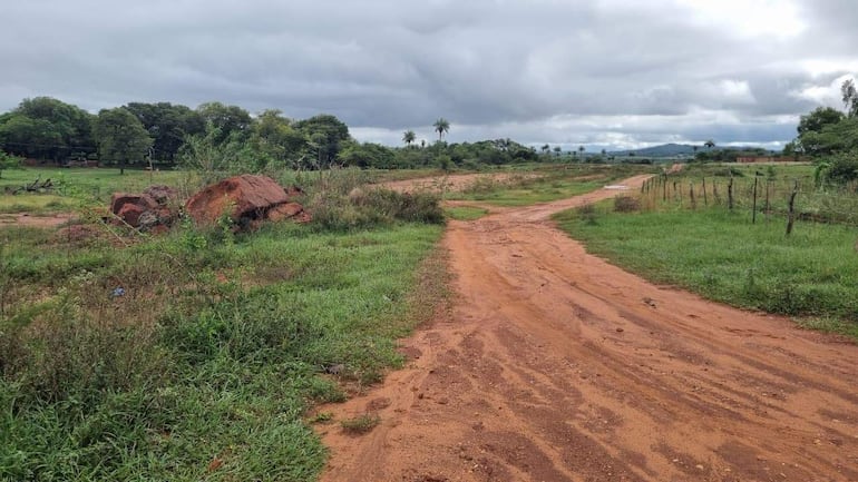 Paisaje rural con camino de tierra colorada y vegetación abundante, sin personas visibles ni actividades en curso.